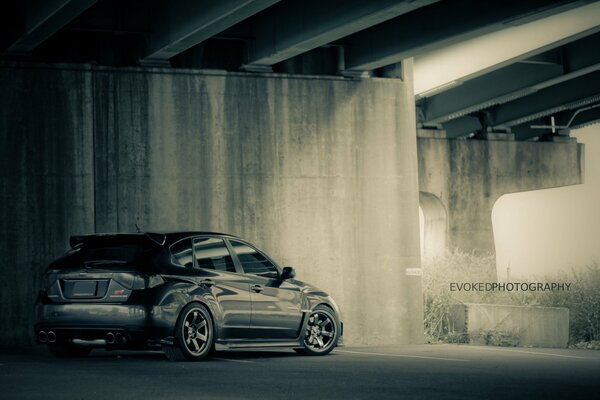 Black Subaru hatchback under the bridge