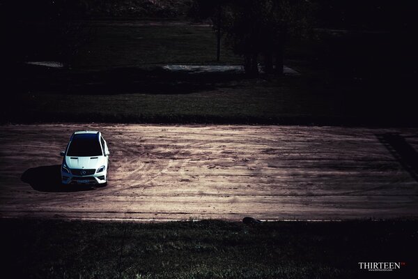 Авторская фотография автомобиля Mercedes-Benz болоснежного цвета, одиноко стоящего на дороге