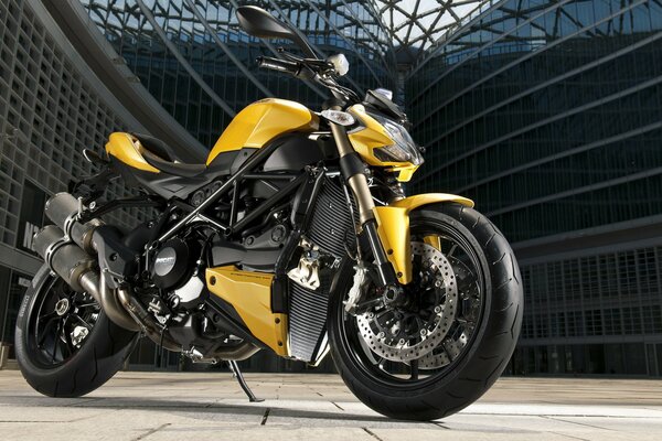 A yellow ducati streetfighter motorcycle stands on an urban background