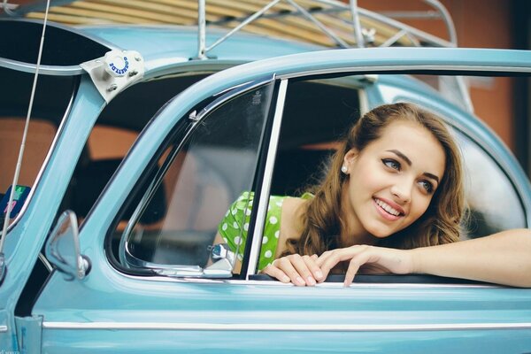 Young girl model driving a retro car
