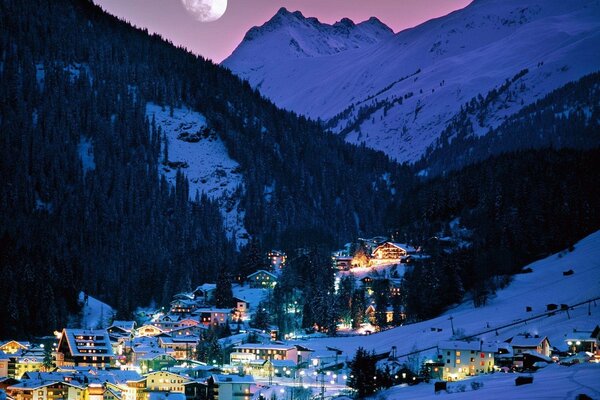 Winter evening in a village under the moon