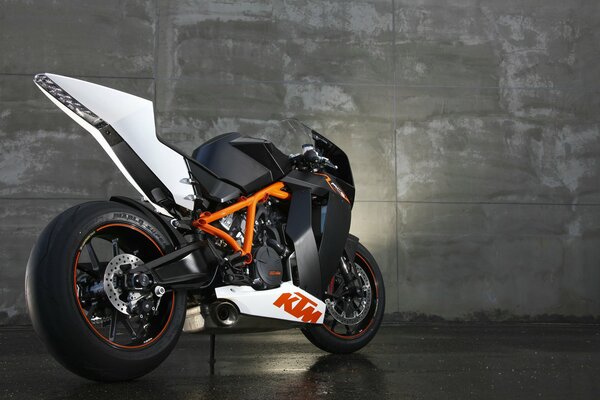 The ktm rc8 sports bike stands against a concrete wall