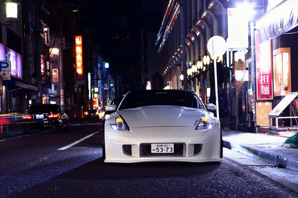 A white Nissan 370z with Fossen wheels stands on a night street