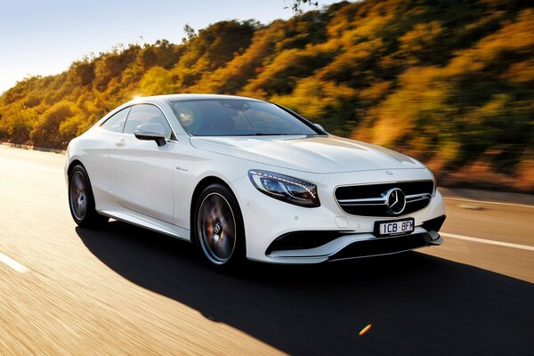 Mercedes blanco corre por la carretera fuera de la ciudad