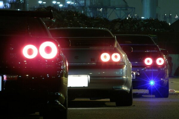 Three cars with their headlights on at night