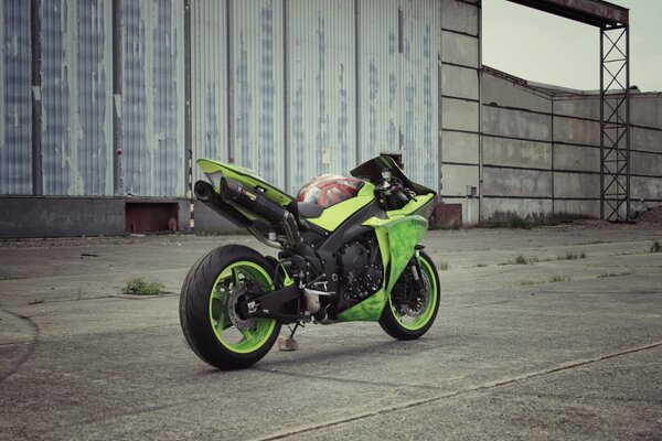 Green motorcycle on the background of an abandoned building