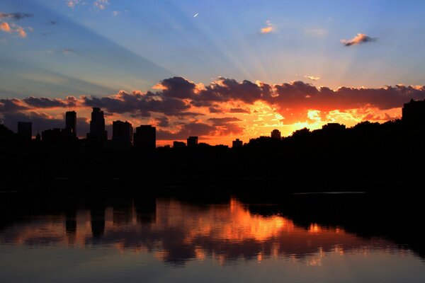 Silhouettes of skyscrapers at sunset by the bay