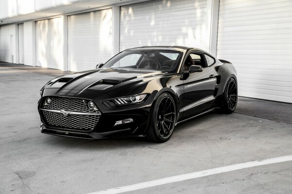 Ford Mustang negro 2015 se encuentra en la puerta de los garajes