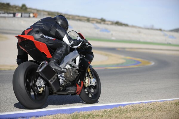 Un hombre monta una moto deportiva aprilia RSV4 negra y roja