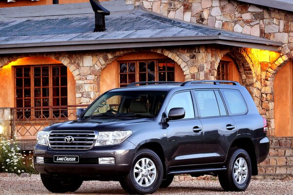 Schwarzer Toyota Land Cruiser vor dem Hintergrund eines Steinhauses mit Bögen