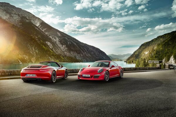 Two red porshe 911 on the background of clouds