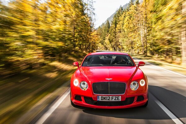 A red Bentley Continental is flying on the highway