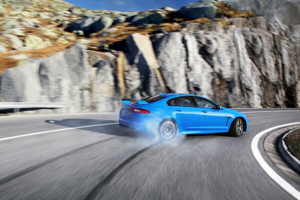 Jaguar XFR-s bleu à la dérive dans les montagnes