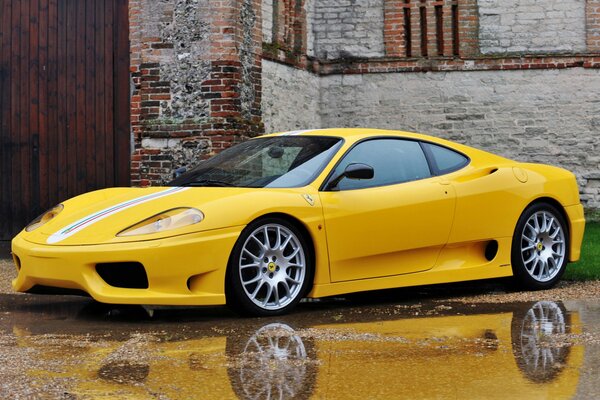 Riflesso di una Ferrari 360 dai toni gialli in una pozzanghera