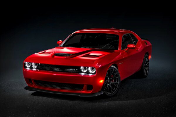 Dodge Challenger rosso su sfondo nero con fari accesi