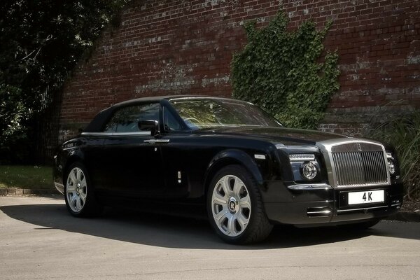 Черный rolls-royce на фоне старой бордовой стены