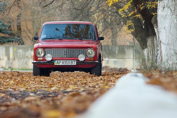 Un coche rojo recorre la carretera de otoño