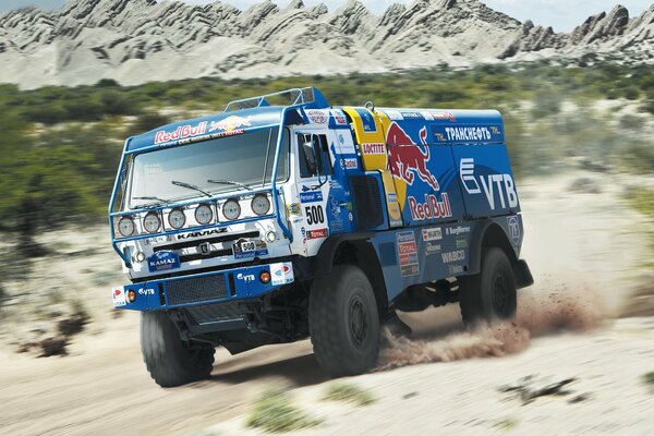 KAMAZ Dakar cavalca sulla sabbia sullo sfondo delle montagne