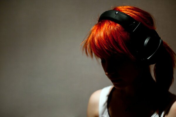 A girl with red hair wearing headphones