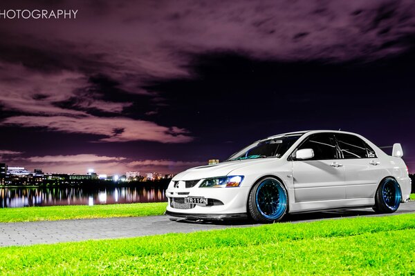 Voiture Mitsubishi sur fond de coucher de soleil et les lumières de la nuit