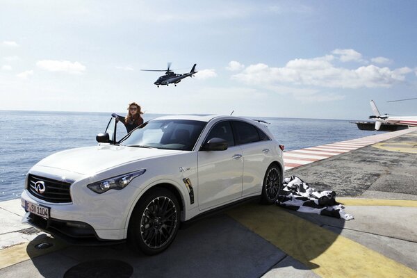 A girl near a car and a helicopter over the sea