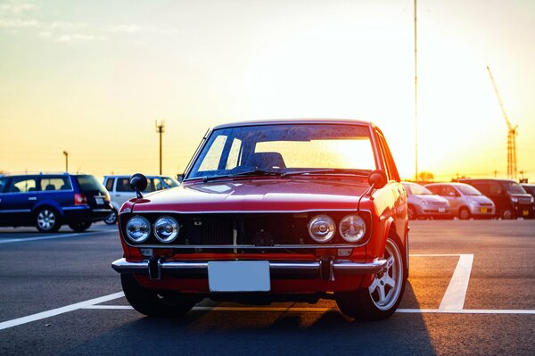 Datsun rosso ai raggi del sole al tramonto