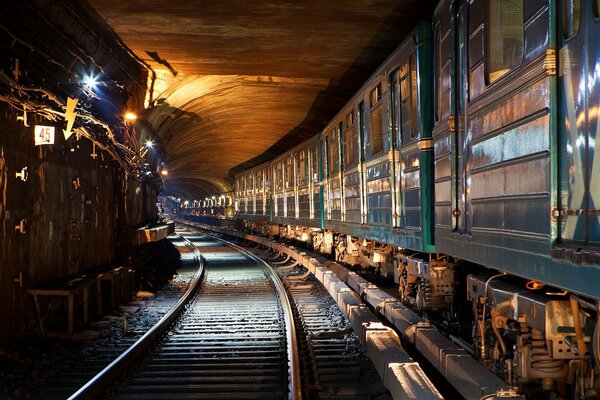 A train arrives from a tunnel illuminated by light