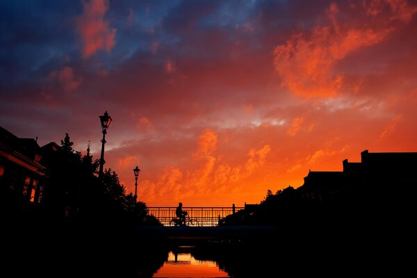 Ciclista che cavalca il ponte durante il tramonto