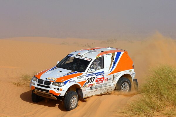 Le SUV bmw x3 au rallye Dakar roule sur une barque de sable