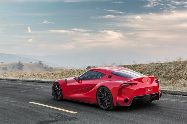 A red car is driving along the road along the desert