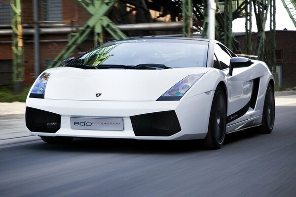 Lamborghini supercar in motion on an asphalt road against the background of a brick building