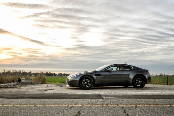 Aston martin en medio de un paisaje rural. Atardecer. Tanque