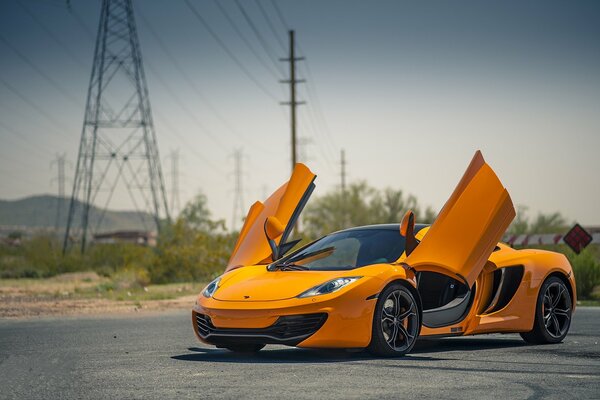 Pomarańczowy McLaren na tle słupów wysokiego napięcia