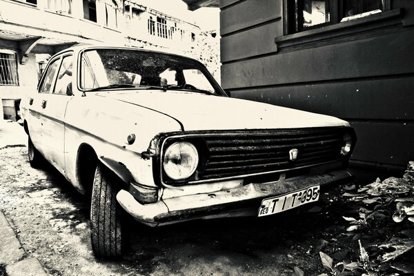 El coche GAZ 24 con el faro roto se encuentra en la casa