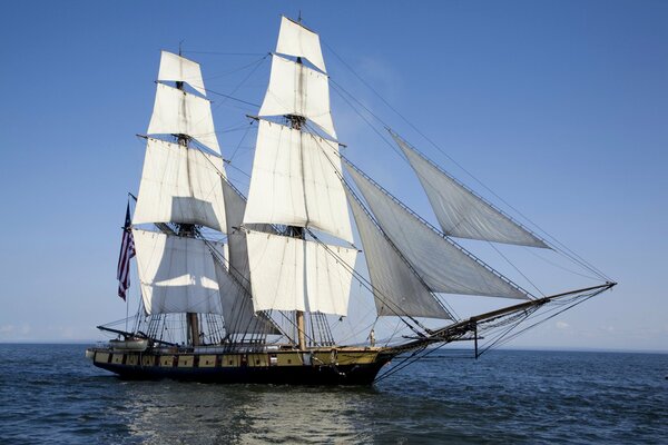 Ein Schiff mit weißen Segeln schwimmt im Meer