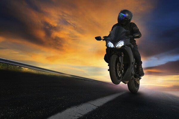 A motorcyclist rides against the background of sunset