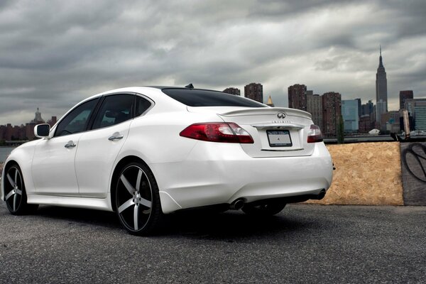 White infiniti on the background of the urban landscape
