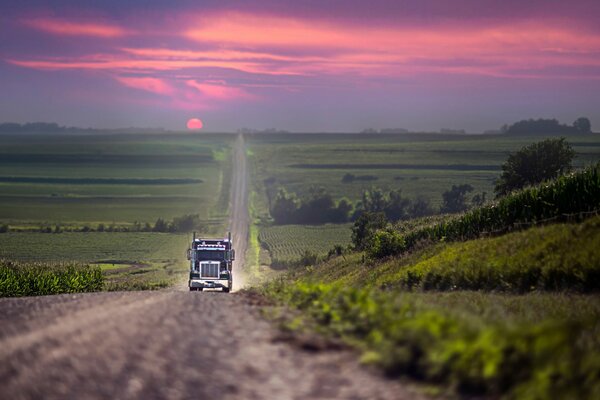 A car is driving along the road with a beautiful sunset