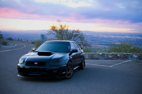 Subaru negro en el fondo de la gran ciudad