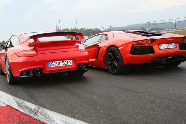 Red Porsche, Lamborghini cars at the start rear view