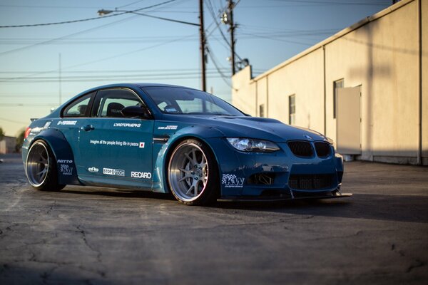 A blue bmw car is standing on the asphalt