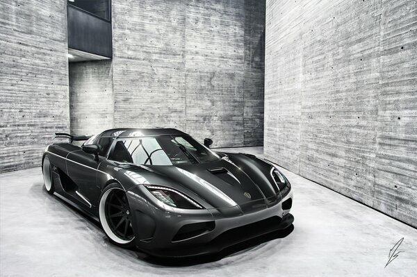 A black car is parked among the brutal gray walls