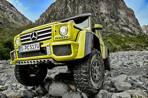 Lime SUV MERCEDES-BENZ G500 4x4 W463 on the background of rocks