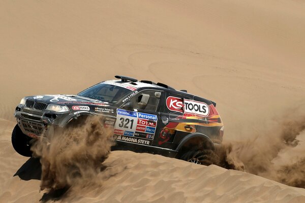 Une BMW X3 noire roule sur des dunes de sable