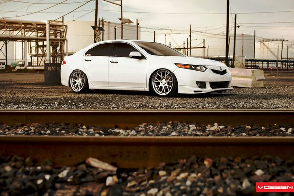 A white car is standing by the railway tracks