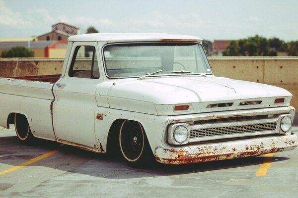 An old white pickup truck in the parking lot