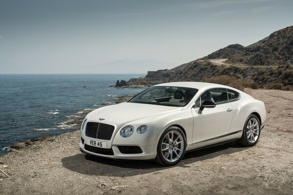 Белый автомобиль bentley на берегу моря