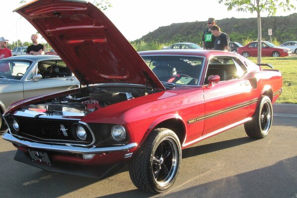 Red Ford car with open hood on the background of mountains