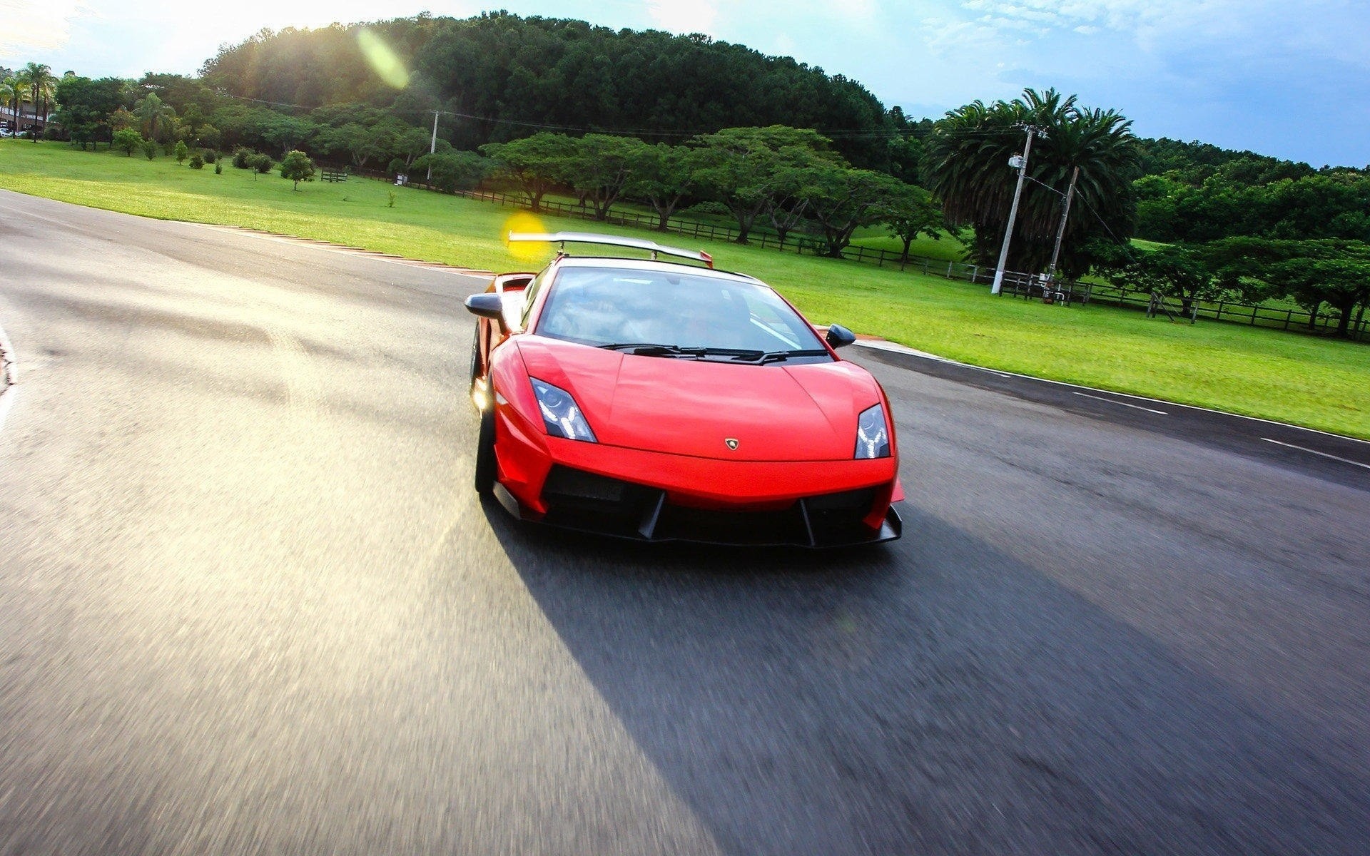 asphalt spoiler red clouds pillars trees grass lamborghini sky road car headlights car wheelbarrow