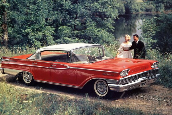 Muzchina y una mujer en un sedán rojo de 1959